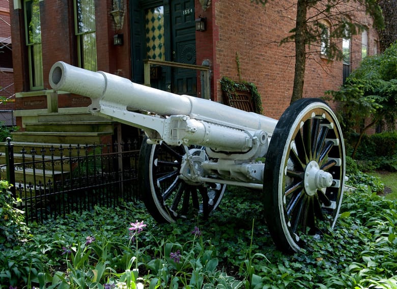 A White cannon sitting in front of a brick building