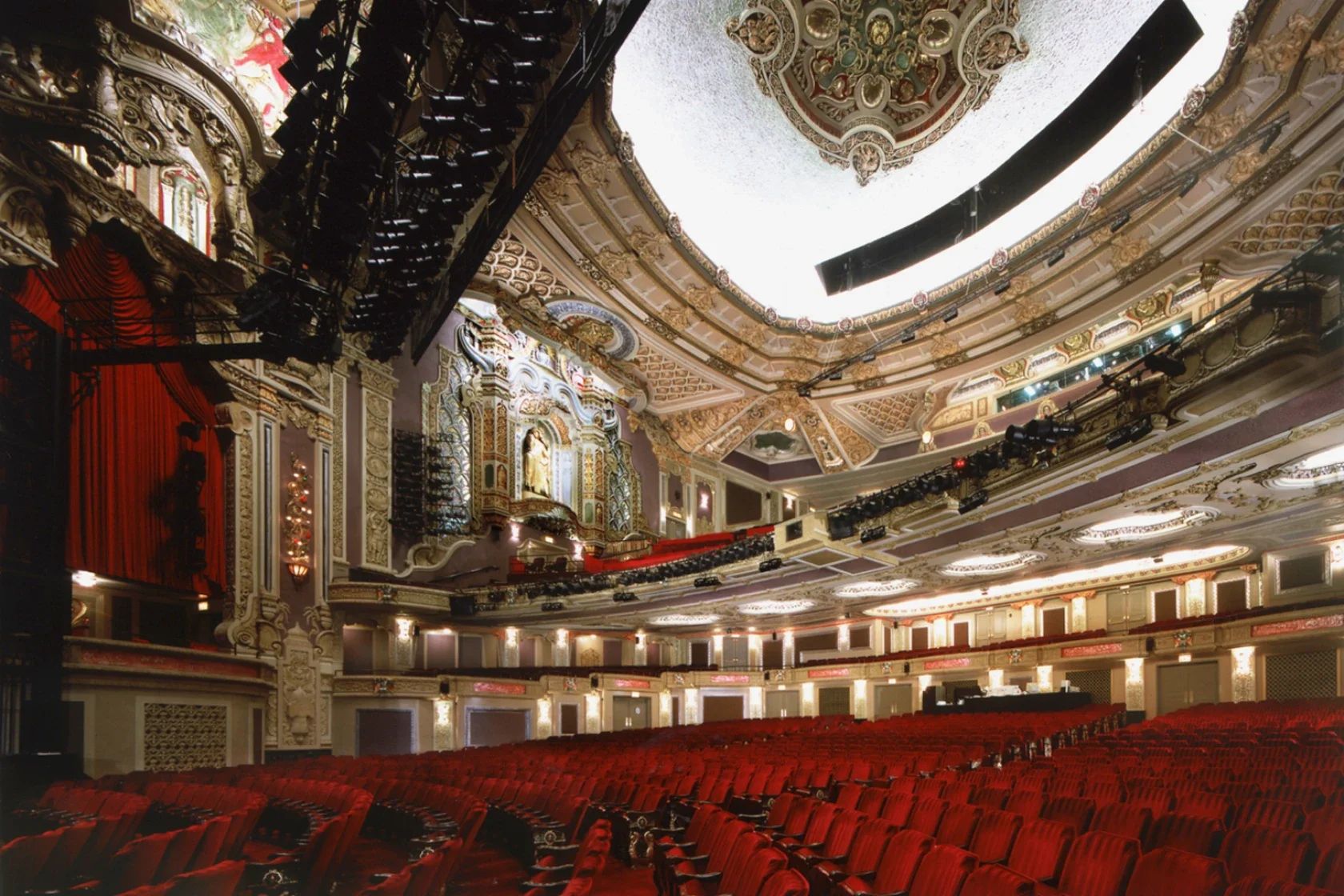 Interior of a theater with gold walls and red velvet chairs