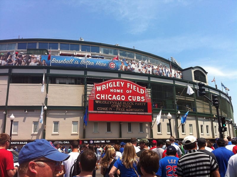 Image of the exterior of Wrigley Field with a large red sign that reads "Wrigley Field, home of the Chicago Cubs"