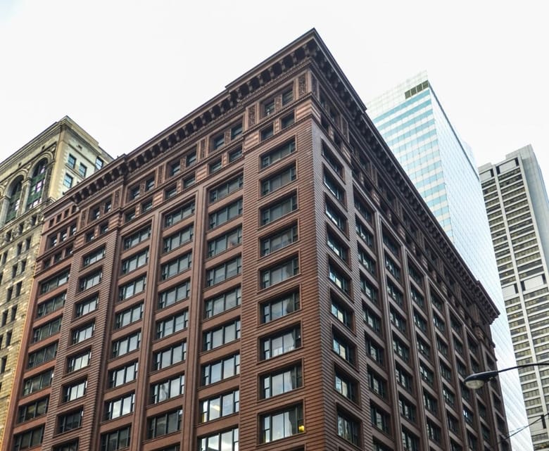 Image looking up at the top of a brown building with details around the edges of the top