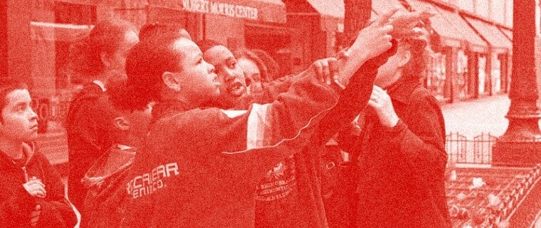 A group of children pointing at a building. The photo has a red overlay