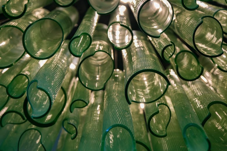 Image looking up at a group of green glass tubes from below.