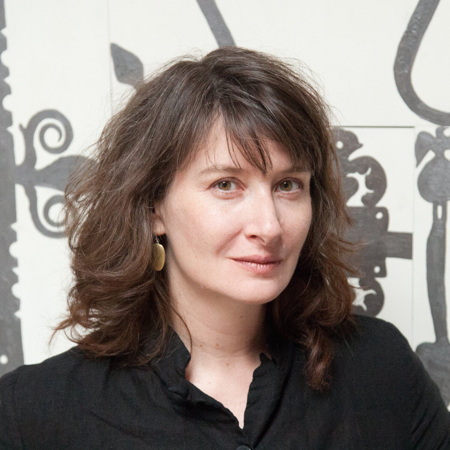 Headshot of a woman with dark hair and bangs in a black button up. 
