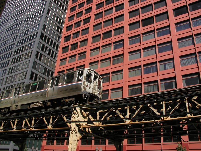 Elevated train passing by modern red-framed building