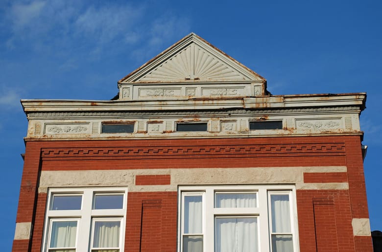 Exterior of weathered stone building, wider shot.
