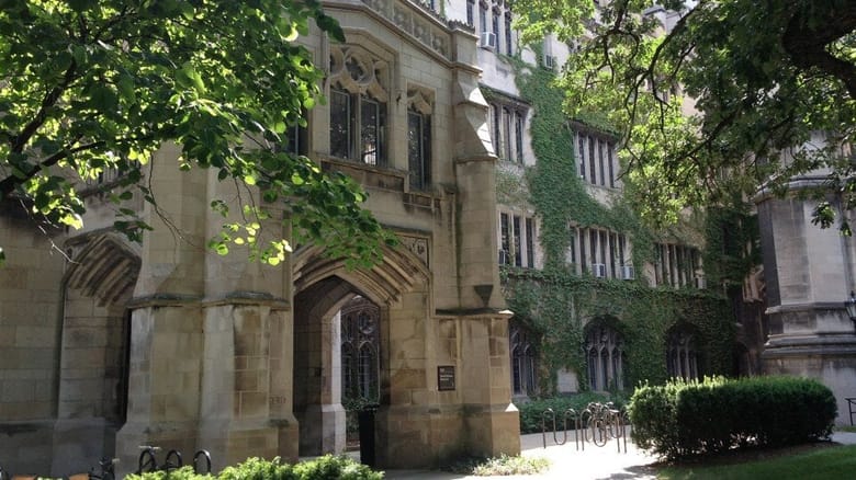 Image of a tan gothic building with green ivy growing up the side.