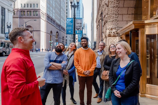 A group of tourists having an engaging interaction with a docent in a red jacket