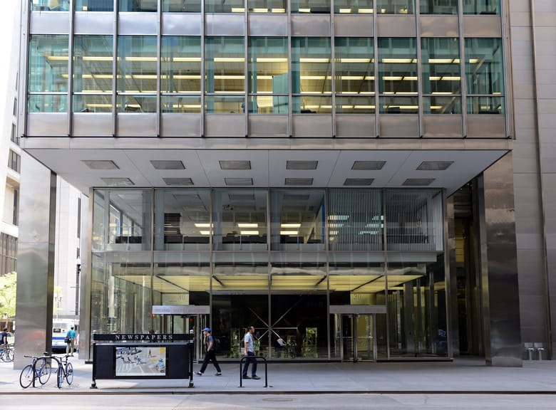 Exterior shot of a building looking into the first floor lobby with large windows allowing you to see a sculpture inside