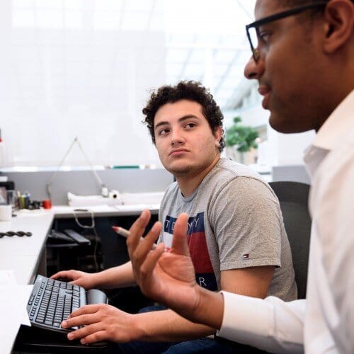 Two male teens in discussion in front of a computer