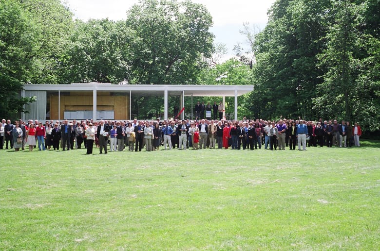 A large group of people standing on grass in front of a modern one level building
