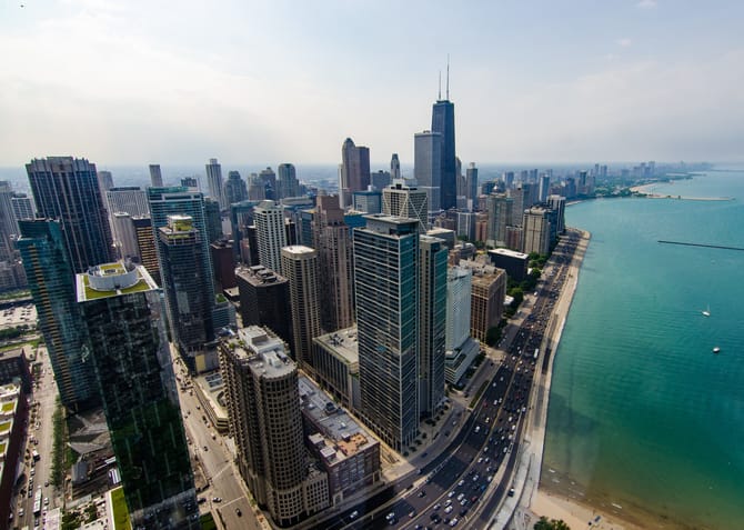 Chicago skyline from above looking north with the lake on the right and tall buildings to the left.