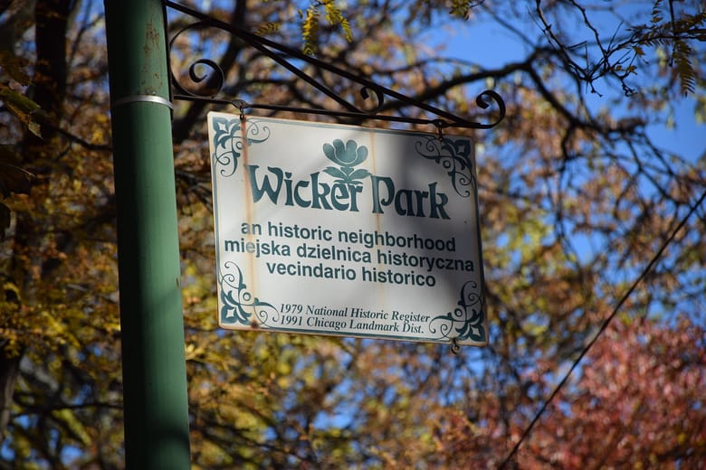 Green sign post holding up a vintage white sign with green text that reads "Wicker Park an historic neighborhood 1979 National Historic Register"