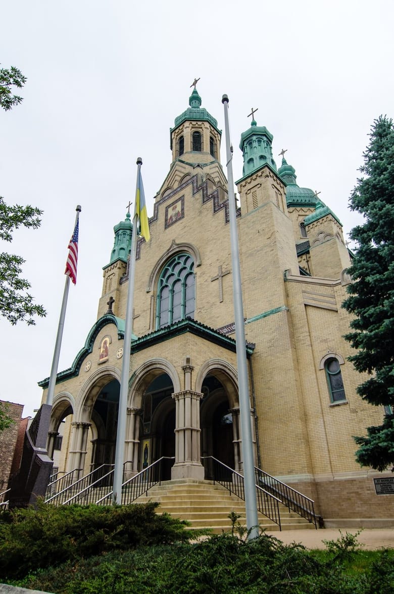 Image of a yellow brick building with green trim and a tower