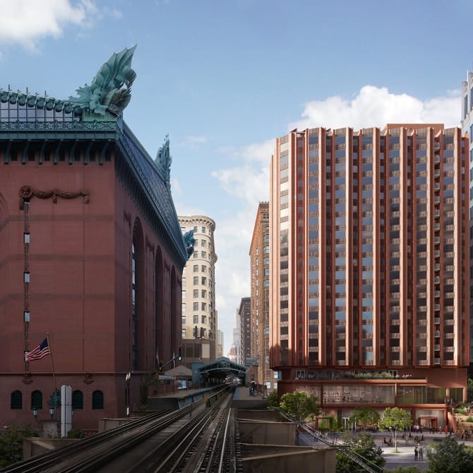 Red brick building with a green roof on the left train tracks in the middle and more brick buildings on the right in the background
