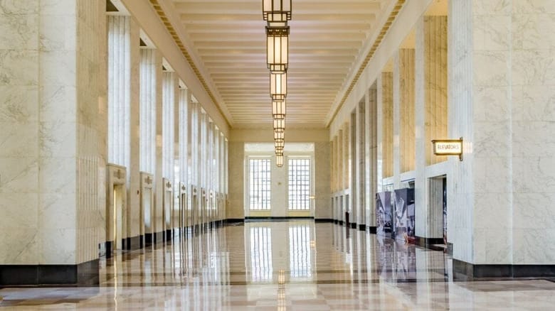 bright marble lobby with inlaid marble compass on floor,brass light fixtures and a vintage elevator sign