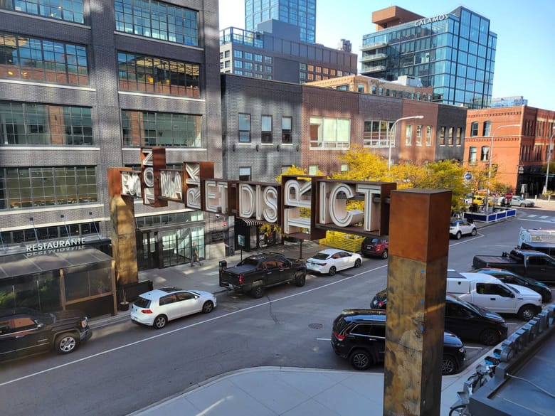Image of a sign that reads "Fulton Market" in block letters and spans over a street