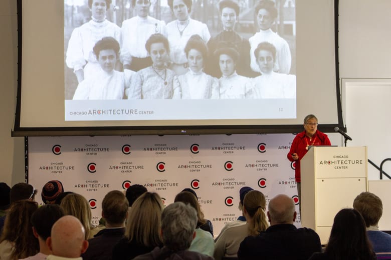 Image of two women walking in front of a white bus parked with the door open