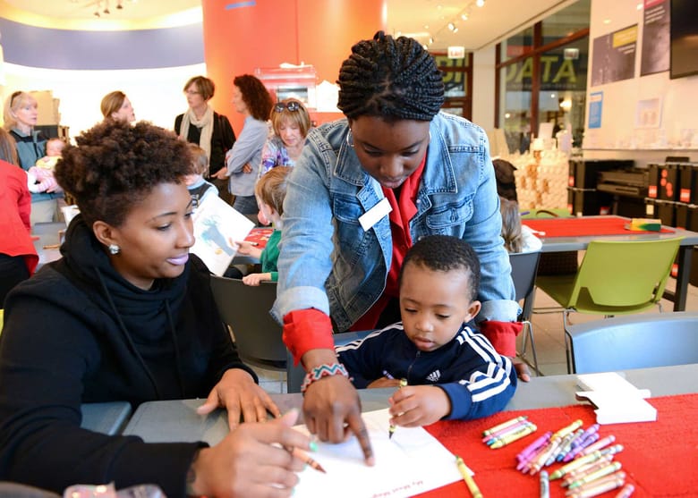 Young black volunteer showing a toddler how to draw