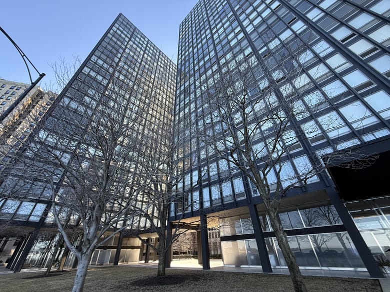 Image from below looking up at a tall rectangular modern black steel building.