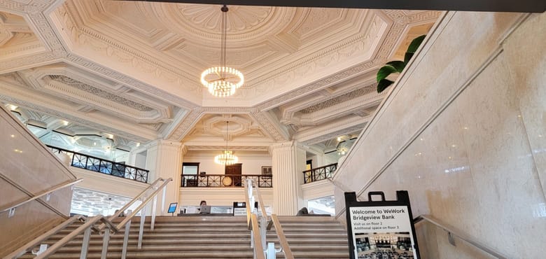 Interior view of large white bank lobby with bright light chandeliers.