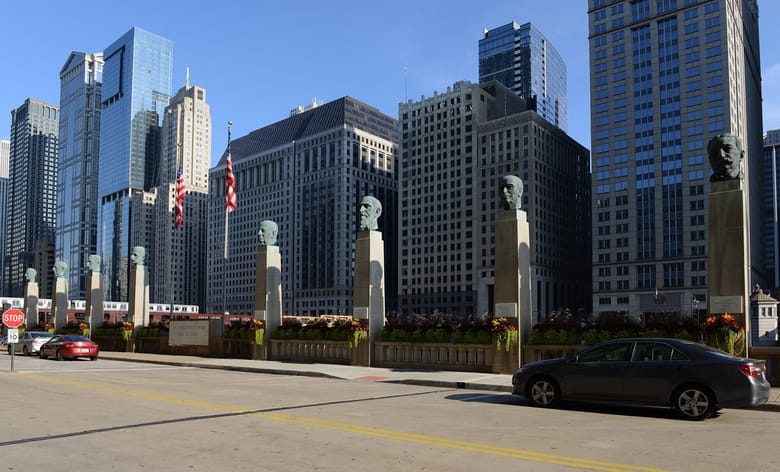 Row of busts on pillars along sidewalk by river