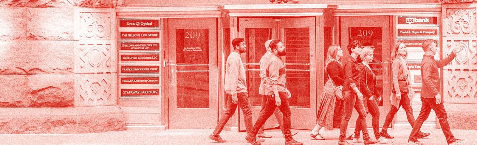 People walking down a city street on a tour. The photo has a red overlay.