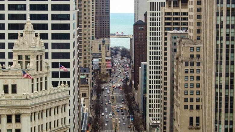 Aerial view down busy city street with tall buildings on either side.