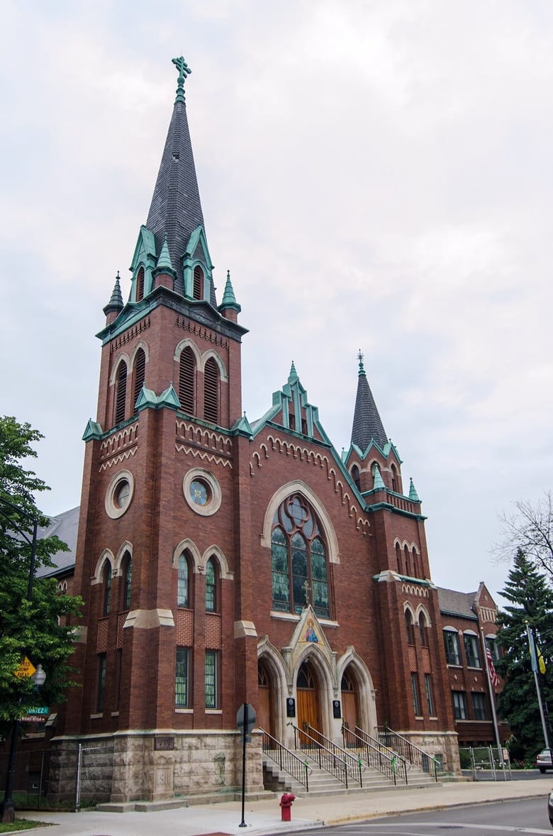 A red brick building with green trim and stain glass.