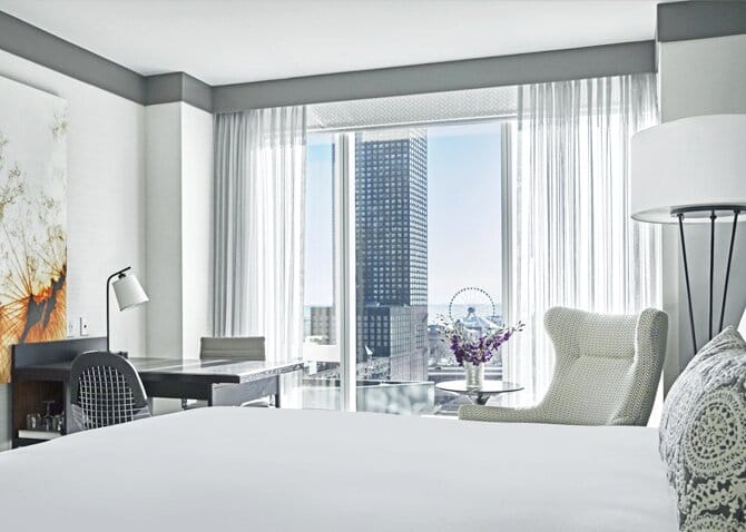 Interior of a modern hotel room with gray and white furniture with a city view