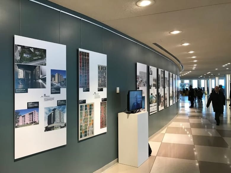 Gallery space with a curved green wall that has informational panels hanging