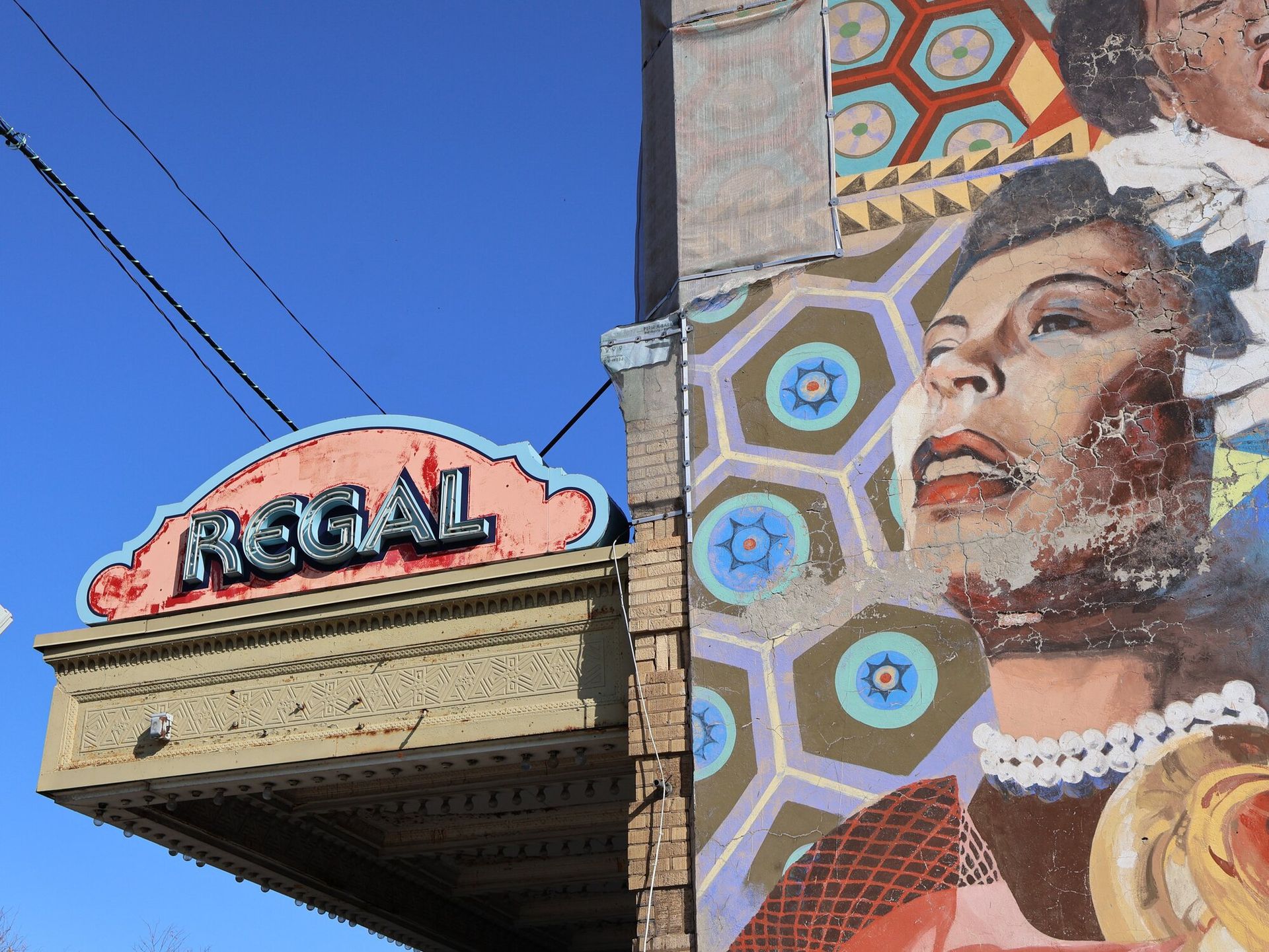 Image of a building with a sign that reads "Regal" and a mural of a woman on the side