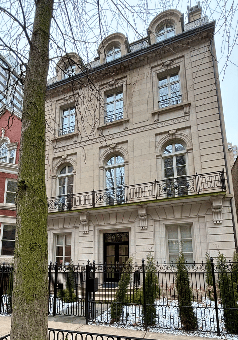 Photo of a three story tan stone house.